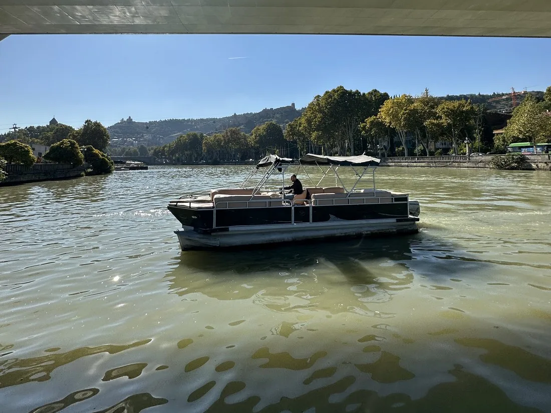 Boat passing under Peace Bridge in Tbilisi